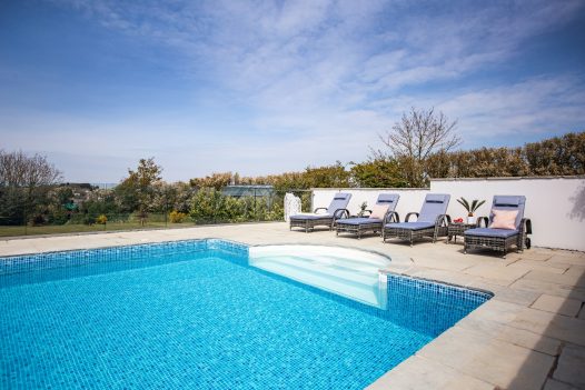 Four recliners alongside the pool at Gwel Mor