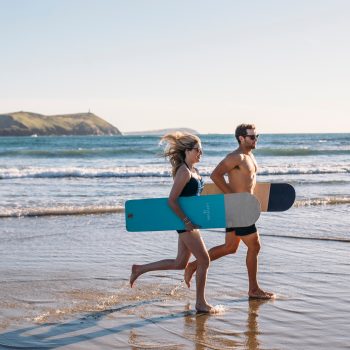 Couple bellyboarding on Polzeath Beach