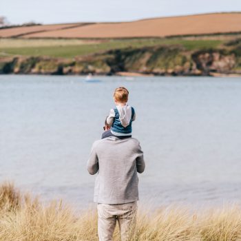 Child on father's shoulders at Rock Beach