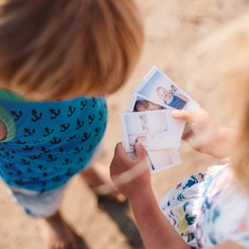 Children with polaroid photos on Polzeath Beach