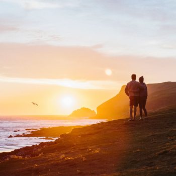 Couple watching the sunset at Polzeath